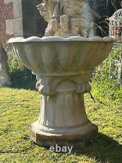 Grande fontaine d'eau en cascade assise avec une jeune fille de campagne tenant un panier de fruits.