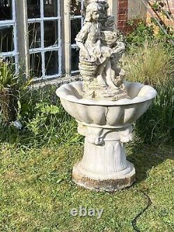 Grande fontaine d'eau en cascade assise avec une jeune fille de campagne tenant un panier de fruits.