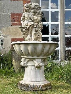 Grande fontaine d'eau en cascade assise avec une jeune fille de campagne tenant un panier de fruits.